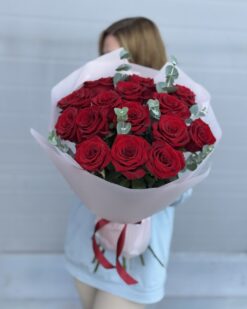 15 красных роз на фоне девушки