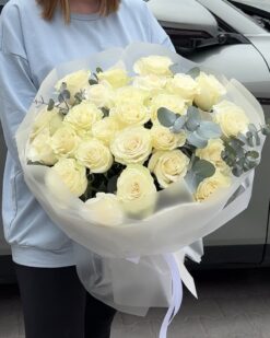 25 белых роз с эвкалиптом на фоне девушки
