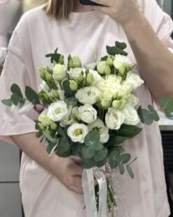 Белый букет невесты из эустомы с эвкалиптом в руках девушки