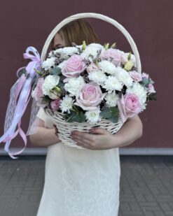 Цветочная композиция в корзине с розами и хризантемами в руках девушки